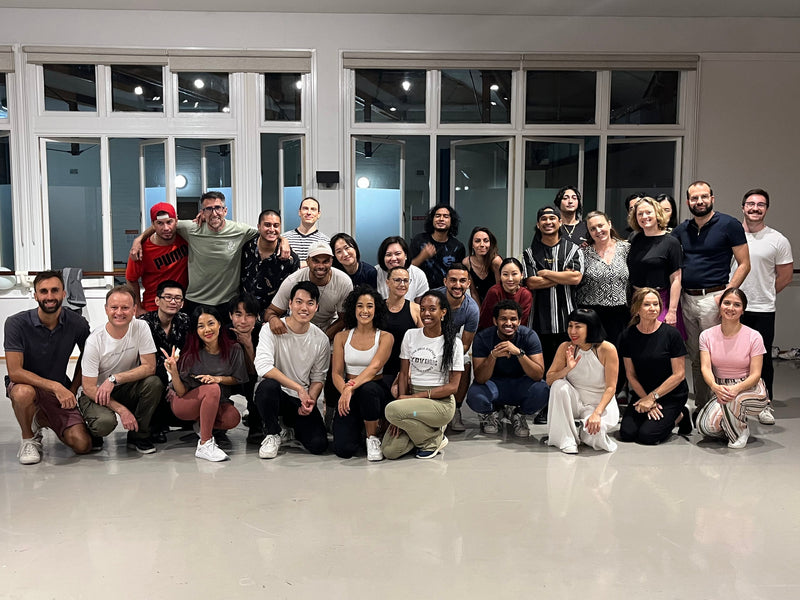 Group of people posing for a photo in a dance studio.