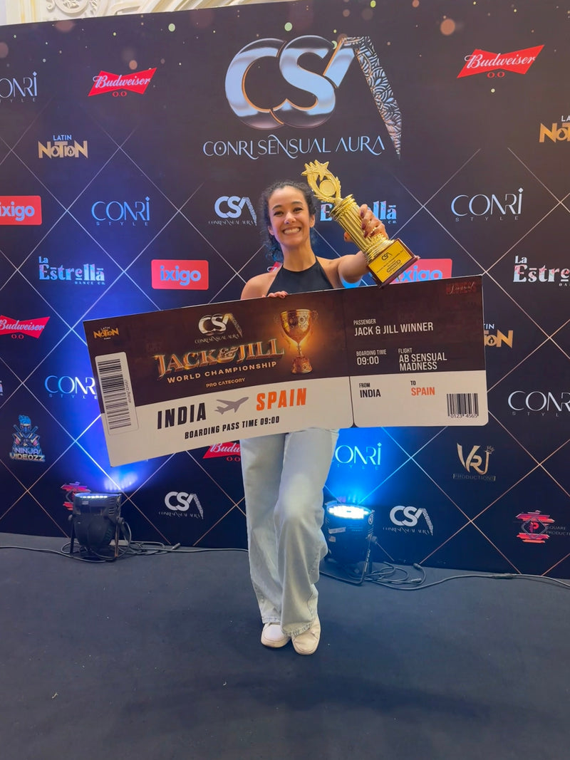 Gemma Jordan holding a first place price and trophy for winning a Pro Bachata Dance Competition in India in 2025